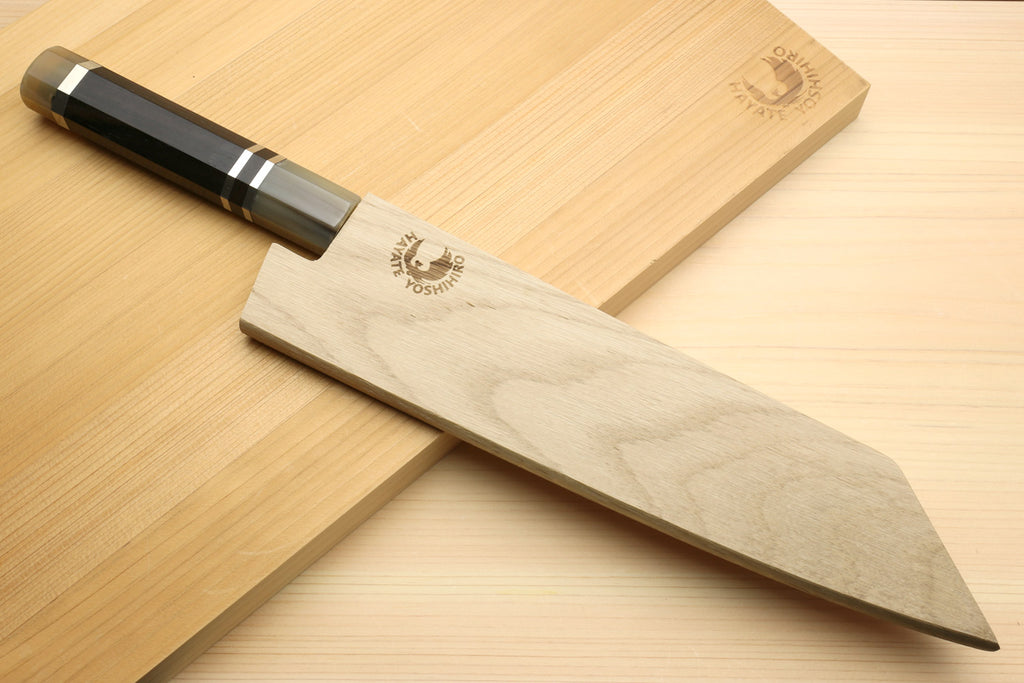 Kiritsuke chef's knife with octagonal ebony handle and wavy damascus blade on board
