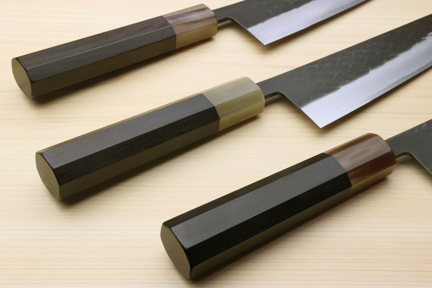 Two Kiritsuke chef knives with dark handles and hammered black blades