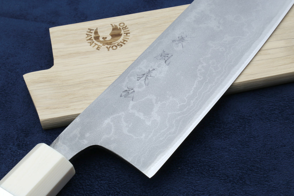 Damascus chef knife with silver blade, white howlite handle and wood stamp near heel