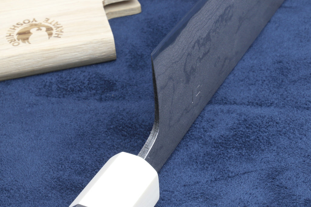 Chef knife with silver damascus blade and white handle near bolster