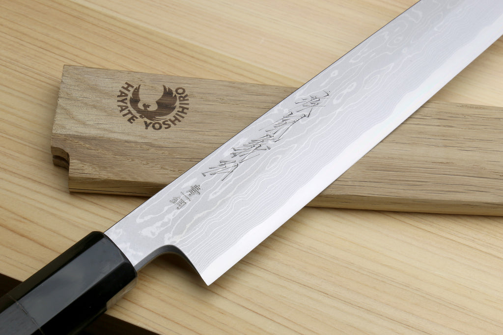 Yanagi sushi knife with white damascus blade, black handle, and wooden sheath
