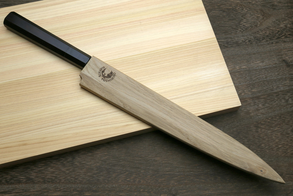 Yanagi sushi knife with black handle and steel damascus blade, beside wooden sheath