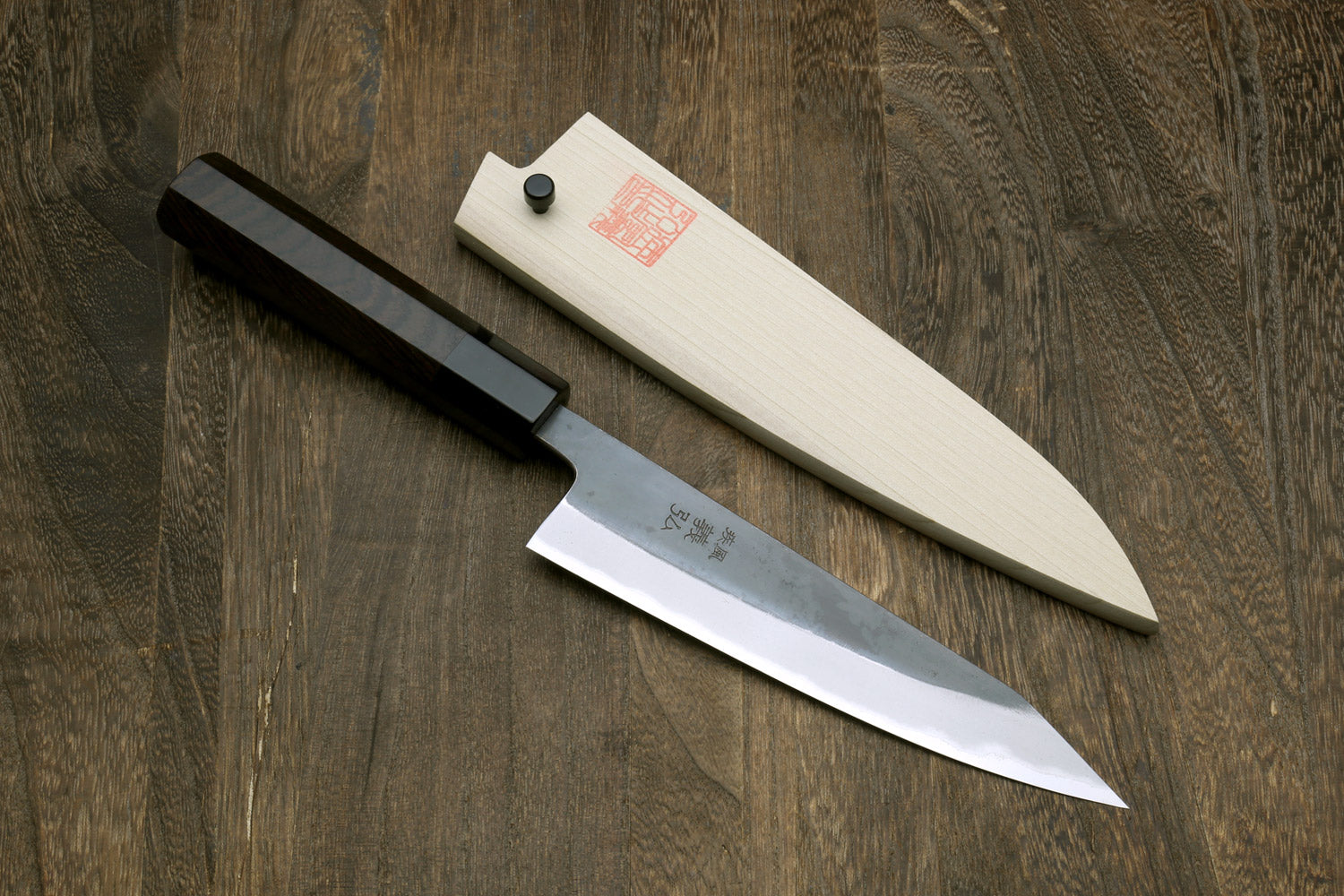 Petty-kiritsuke knife with dark blade and ebony wood handle, side view