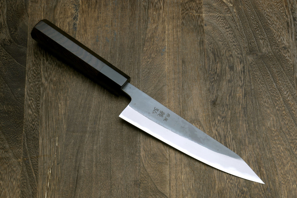 Petty-kiritsuke knife with dark blade and ebony wood handle, angled close view