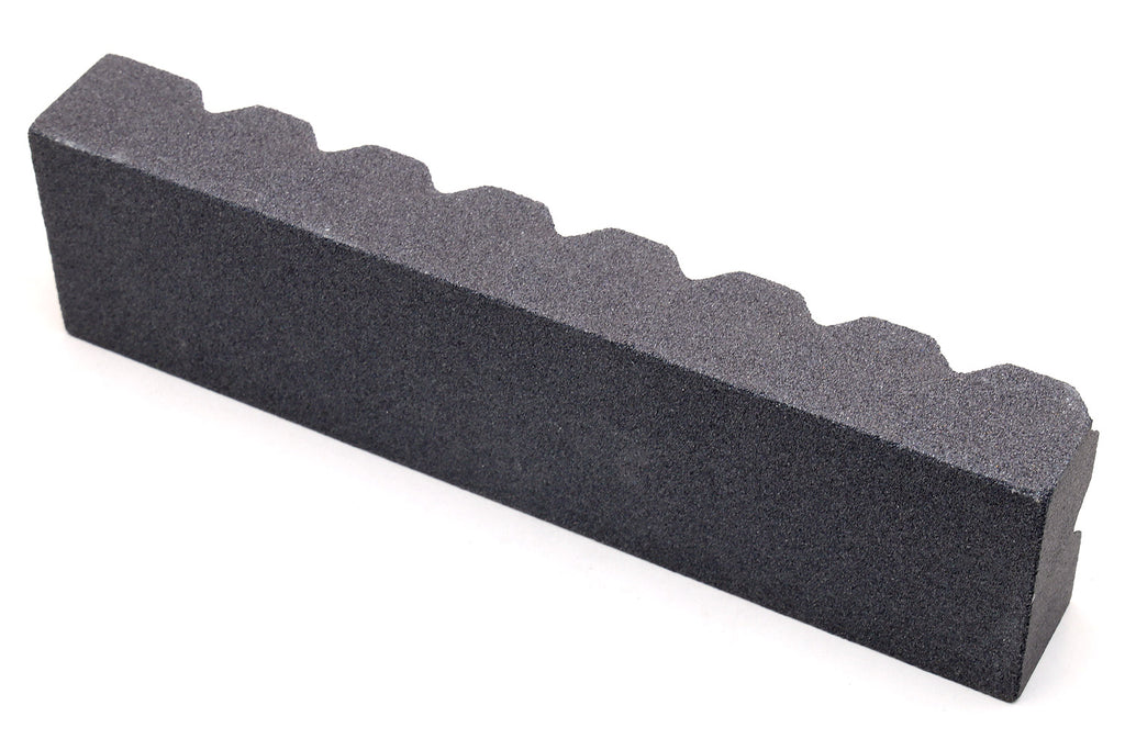 Black sharpening stone with scalloped notches along the top edge