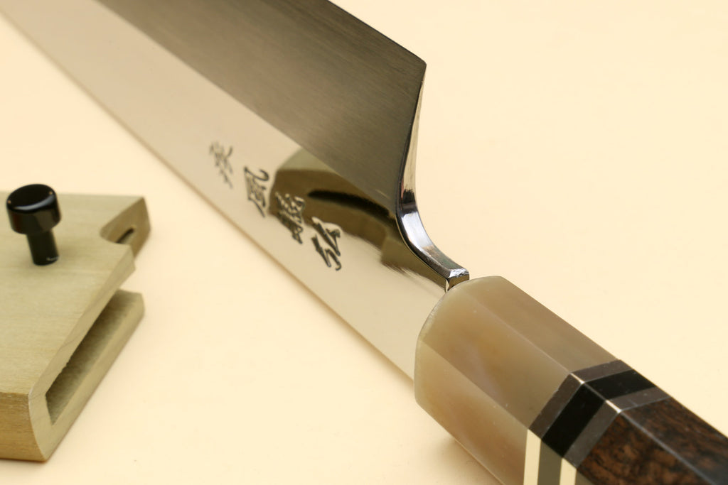 Kiritsuke Japanese knife blade and dark handle with triple-ring detail, close-up