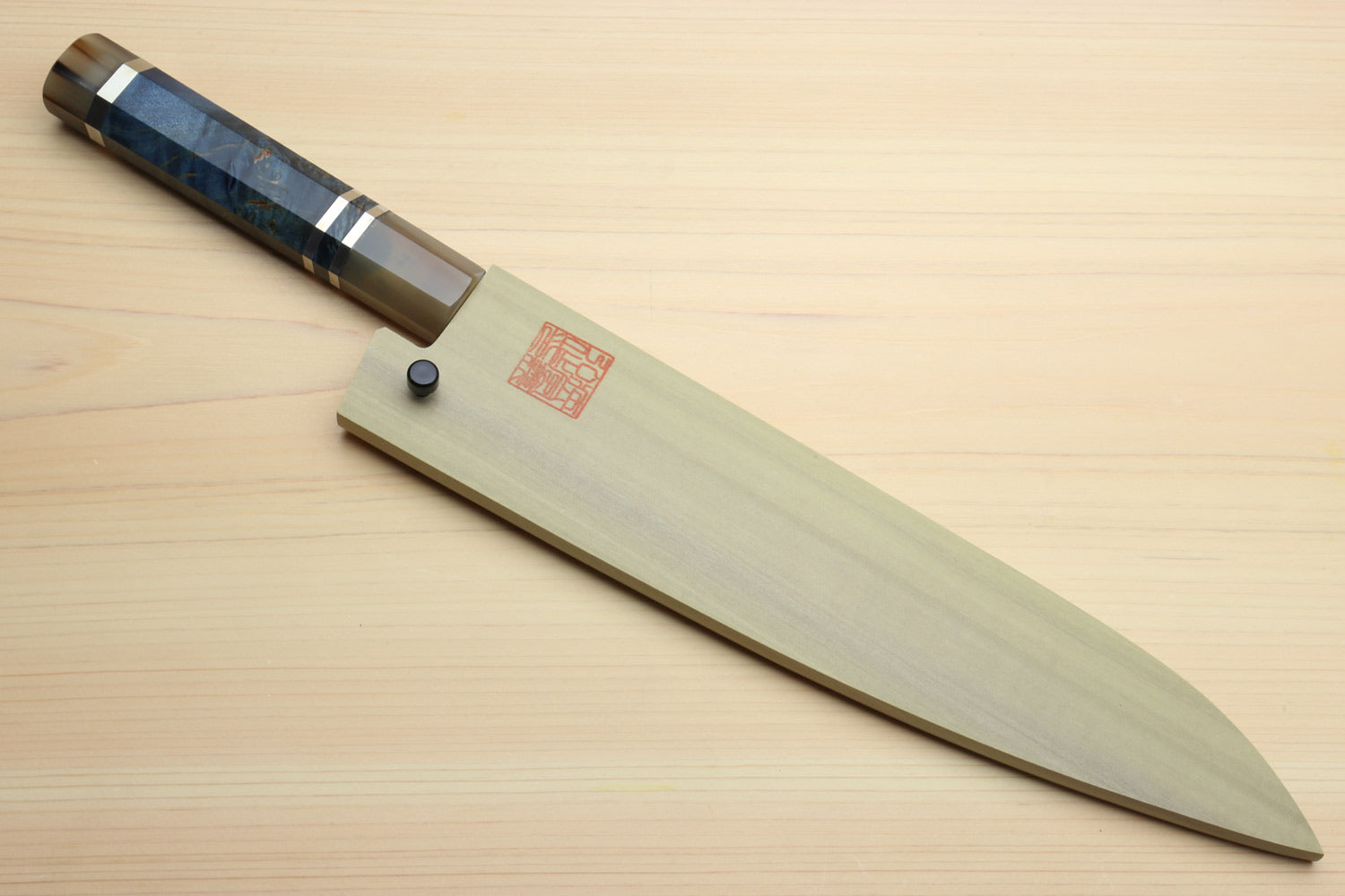 Chef gyuto knife on board with ocean blue octagonal handle and grey Damascus blade