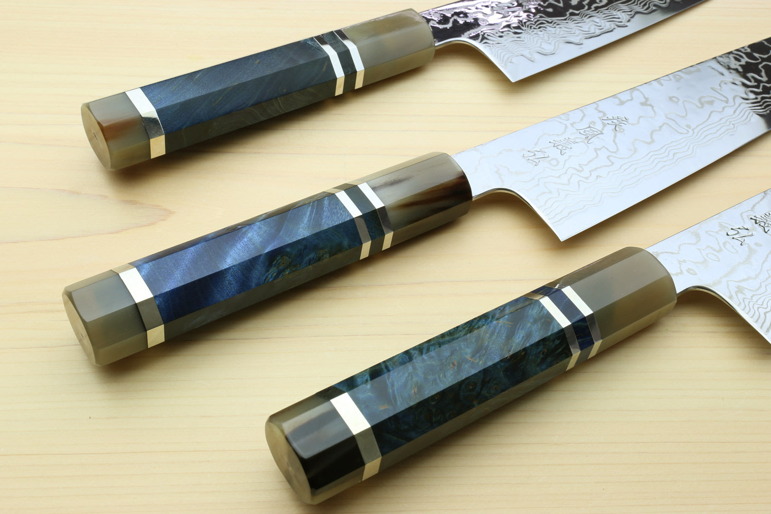 Two kiritsuke chef knives with blue octagonal handles and damascus blades