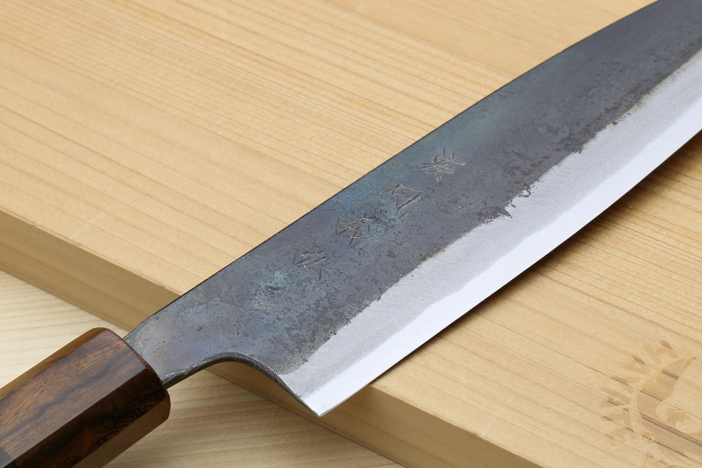 Close-up of petty utility knife blade with kurouchi texture and ebony bolster