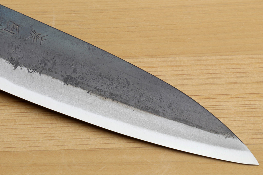 Petty utility knife blade close-up with kurouchi texture and sharpened edge