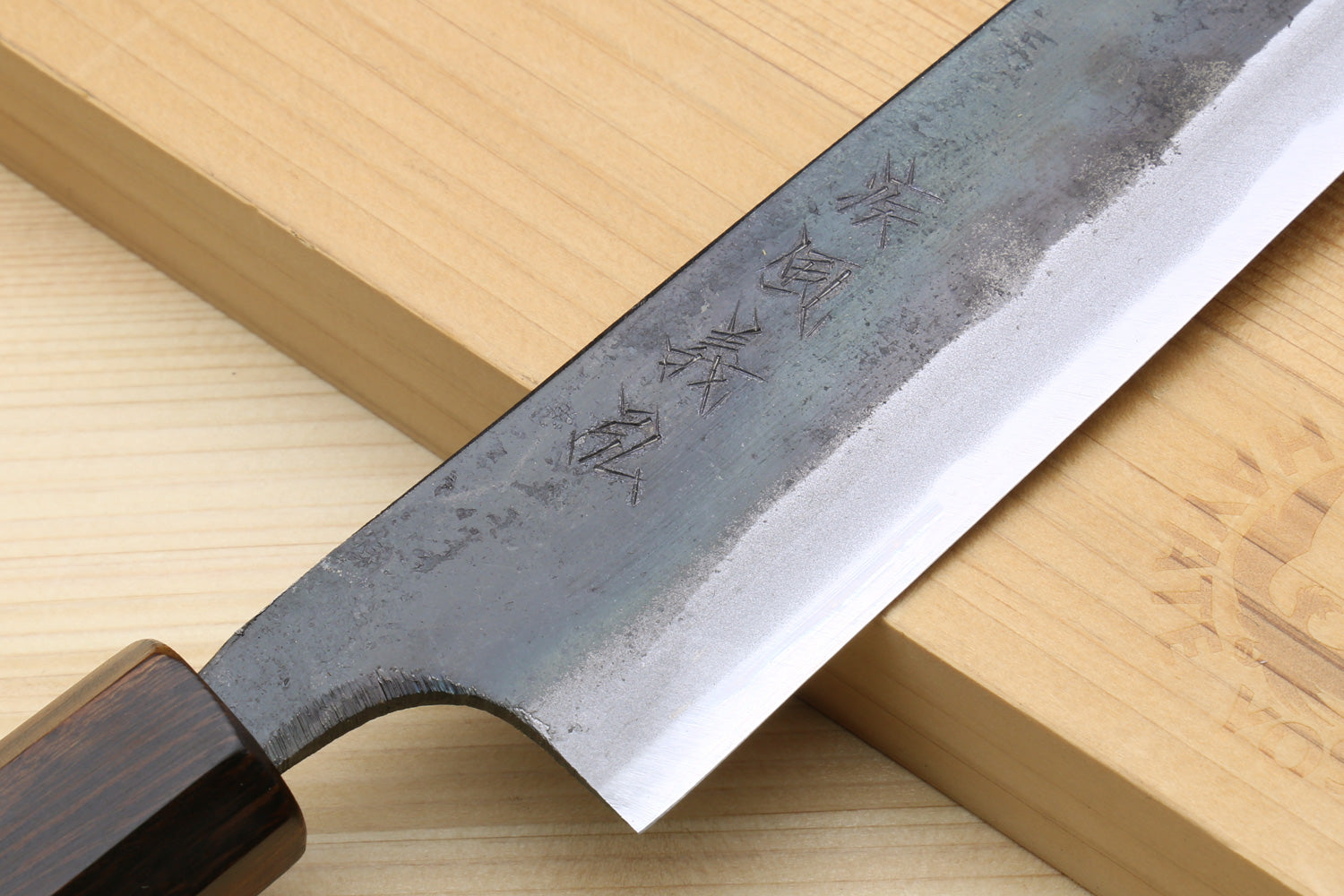 Utility knife blade close-up with engraved marks and dark patina finish