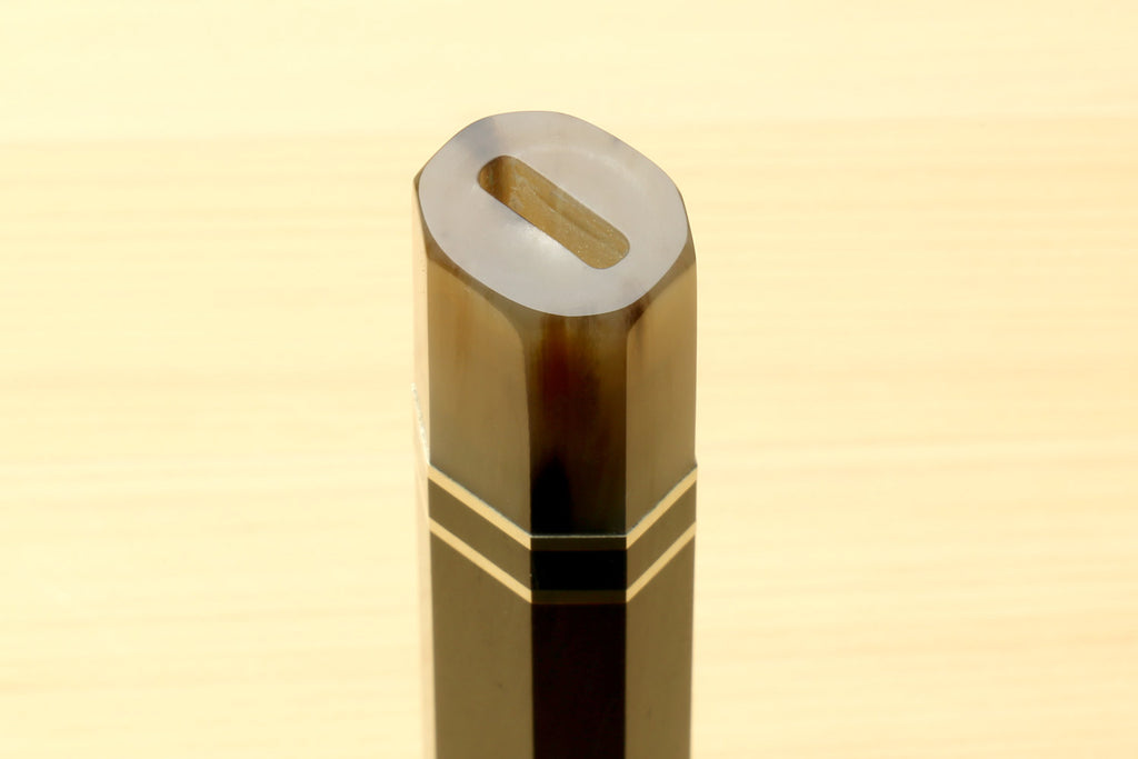 Chef knife handle end with horn bolster and triple ring stripes, thumb slot visible