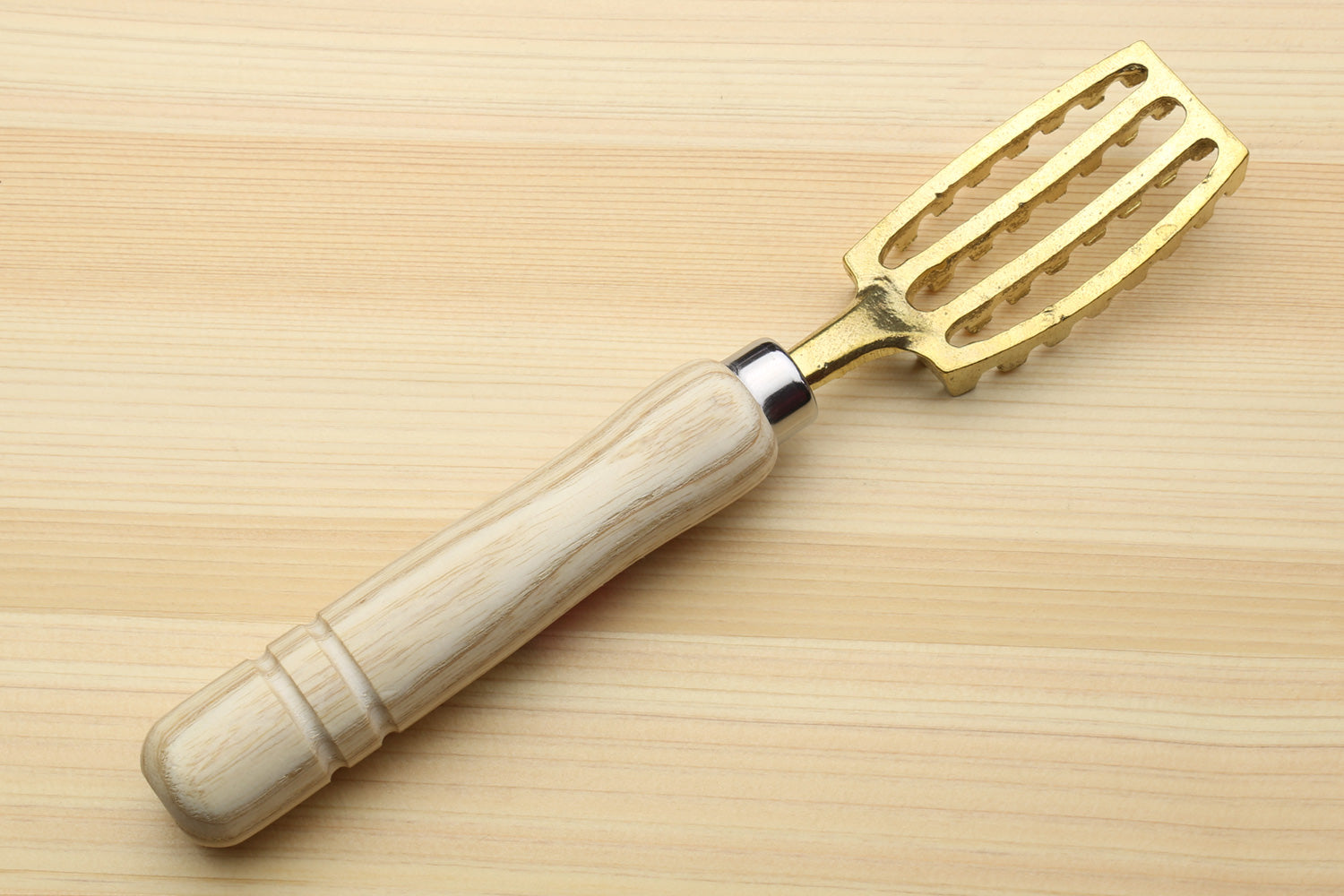 Large fish scaler tool with light wood handle and gold-toned slotted blade