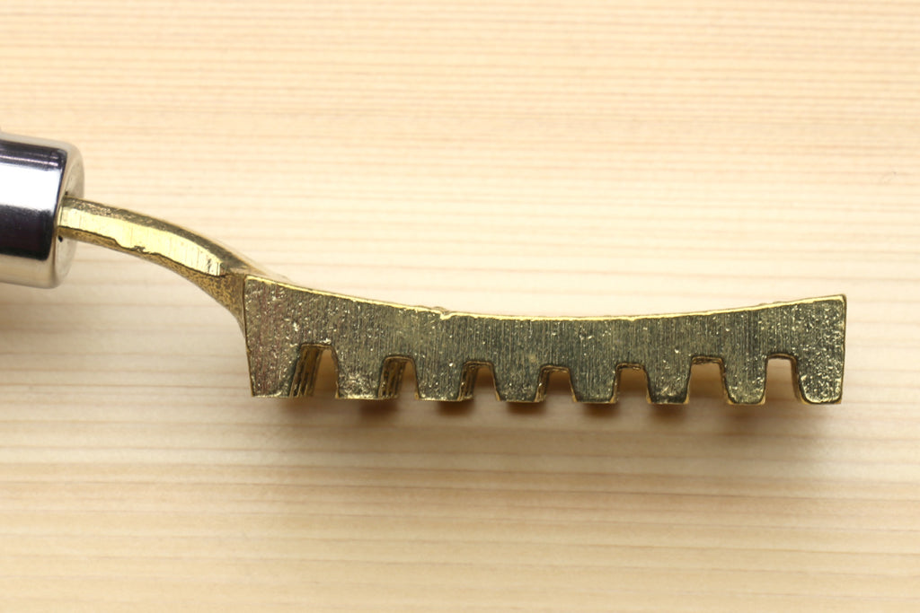 Large fish scaler tool blade end with serrated teeth and gold-toned finish