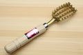 Fish scaler tool with light wood handle and gold metal teeth, pink label on handle