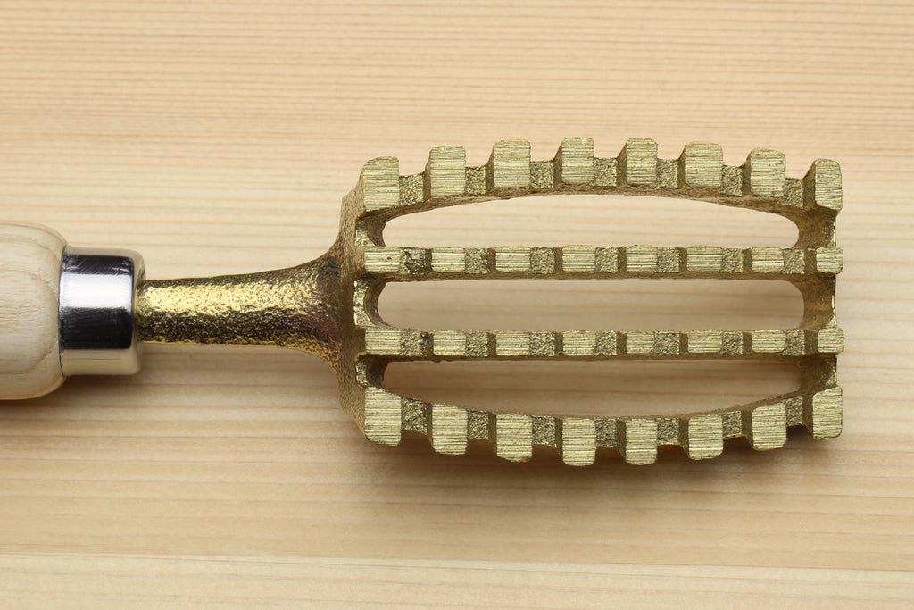 Fish scaler tool with gold metal head featuring multiple rows of teeth