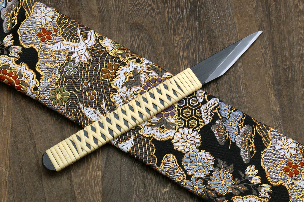 Kiridashi utility knife with beige braided handle and silver blade on patterned cloth
