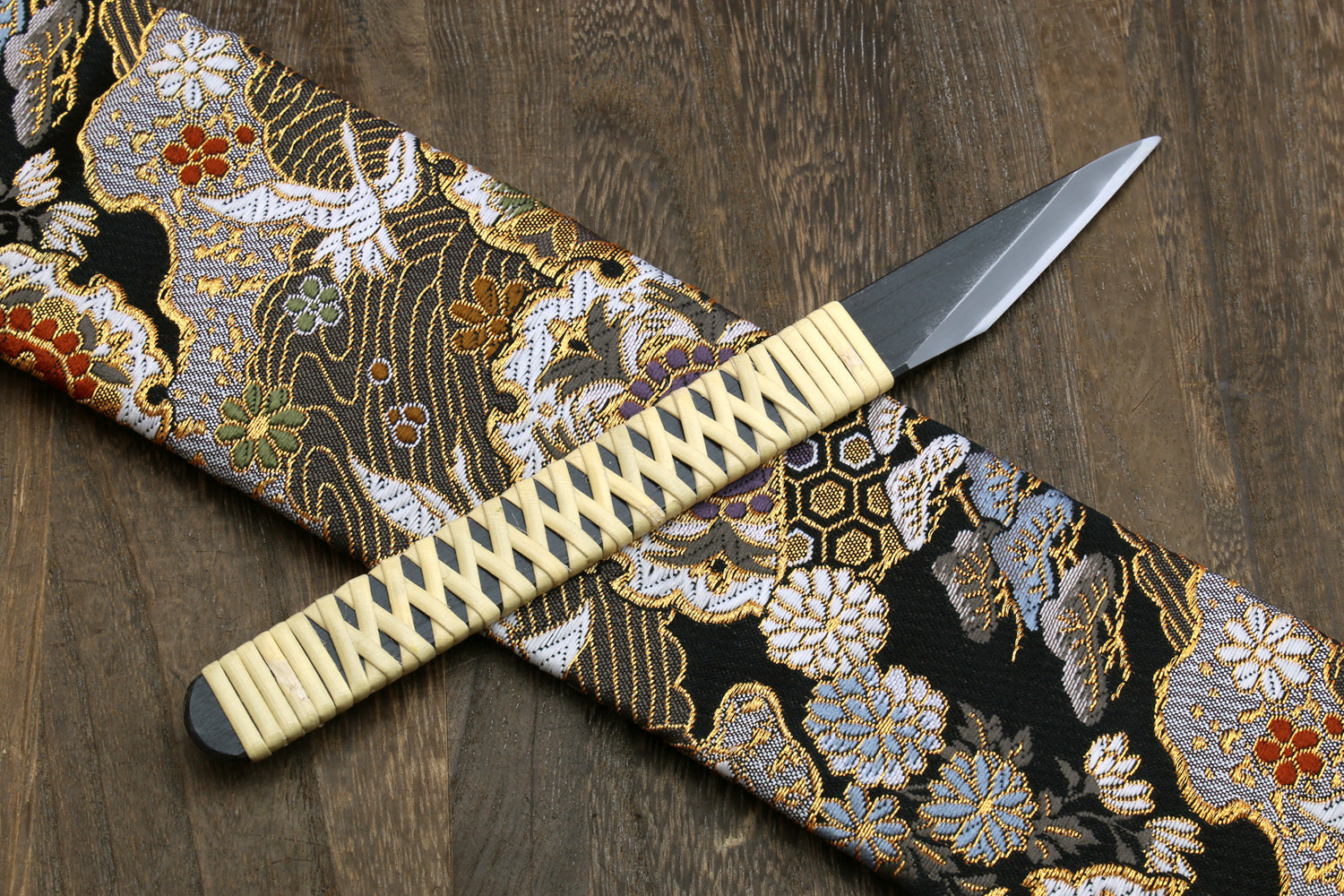 Kiridashi utility knife with beige braided handle and silver blade on patterned cloth