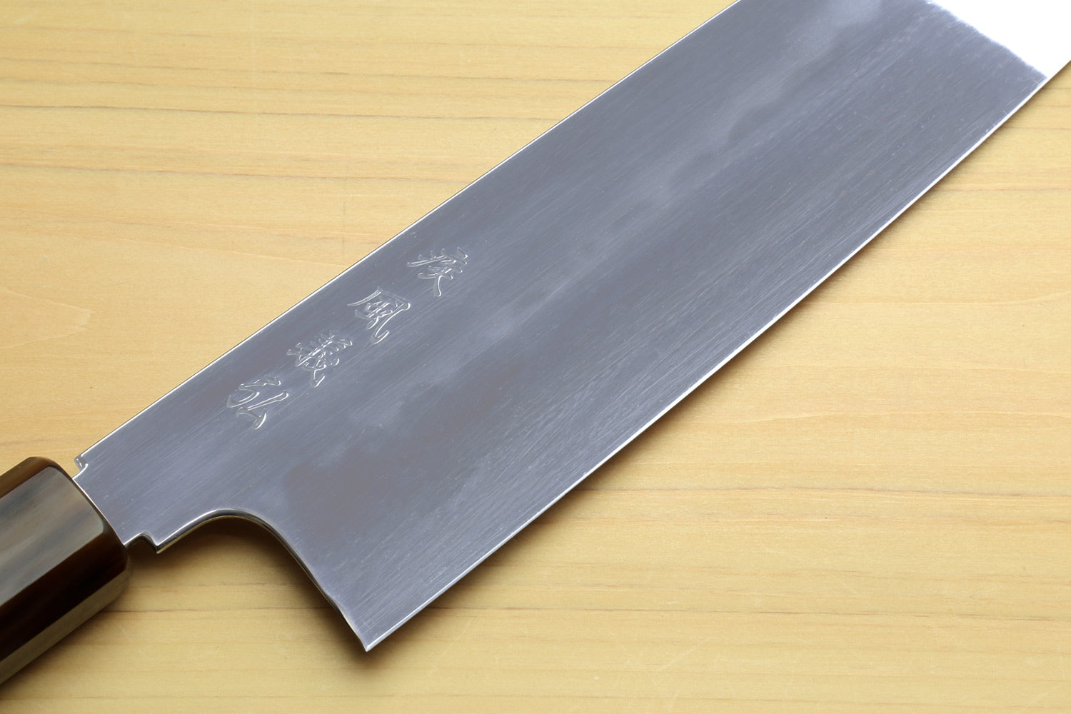 Gyuto chef knife blade with etched markings and dark wooden handle