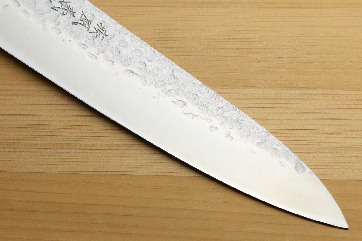 Chef's gyuto knife with engraved hammered stainless blade on wooden surface