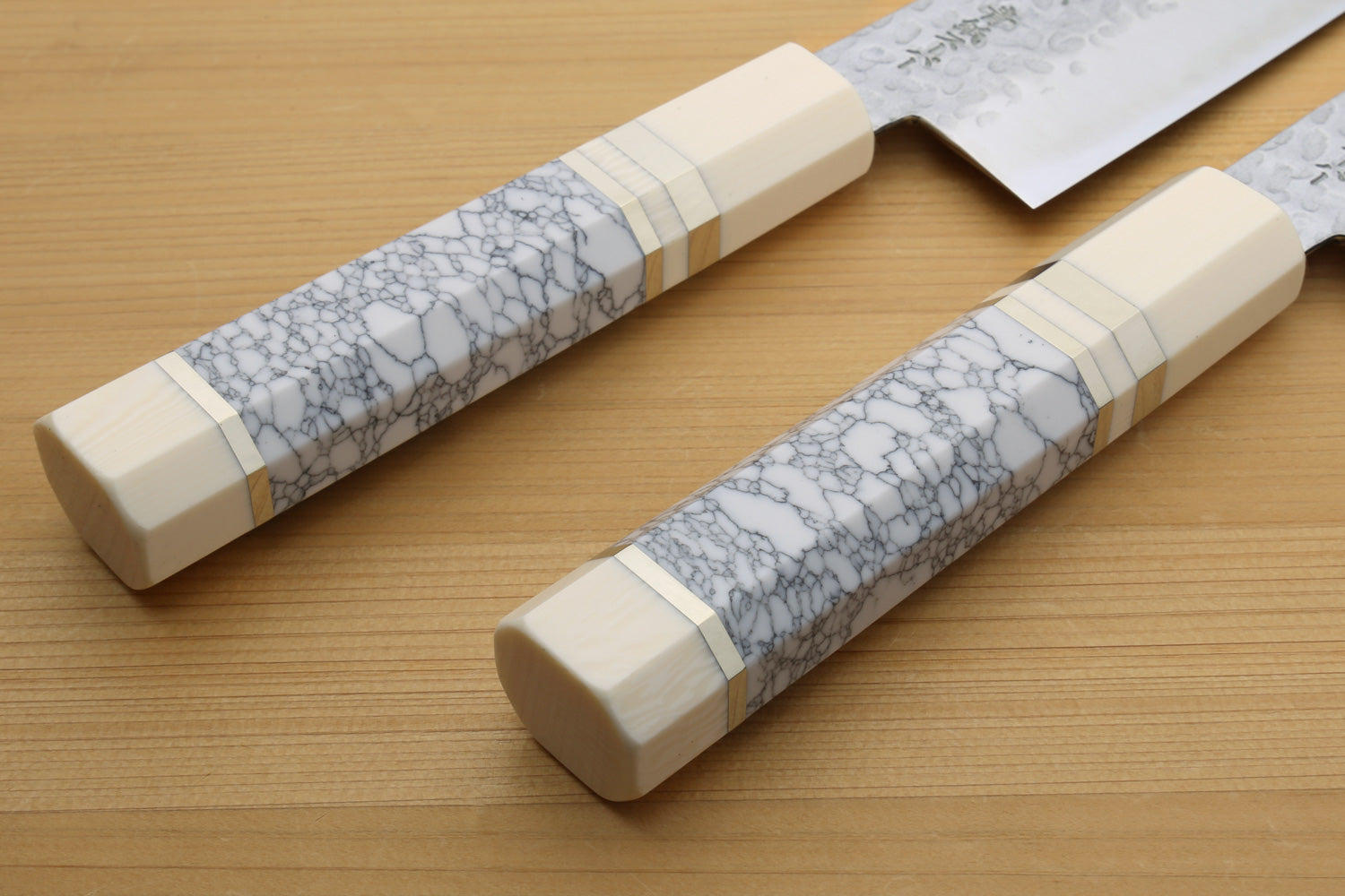 Chef's gyuto knife handles with white and gray crackle-pattern scales and bolster