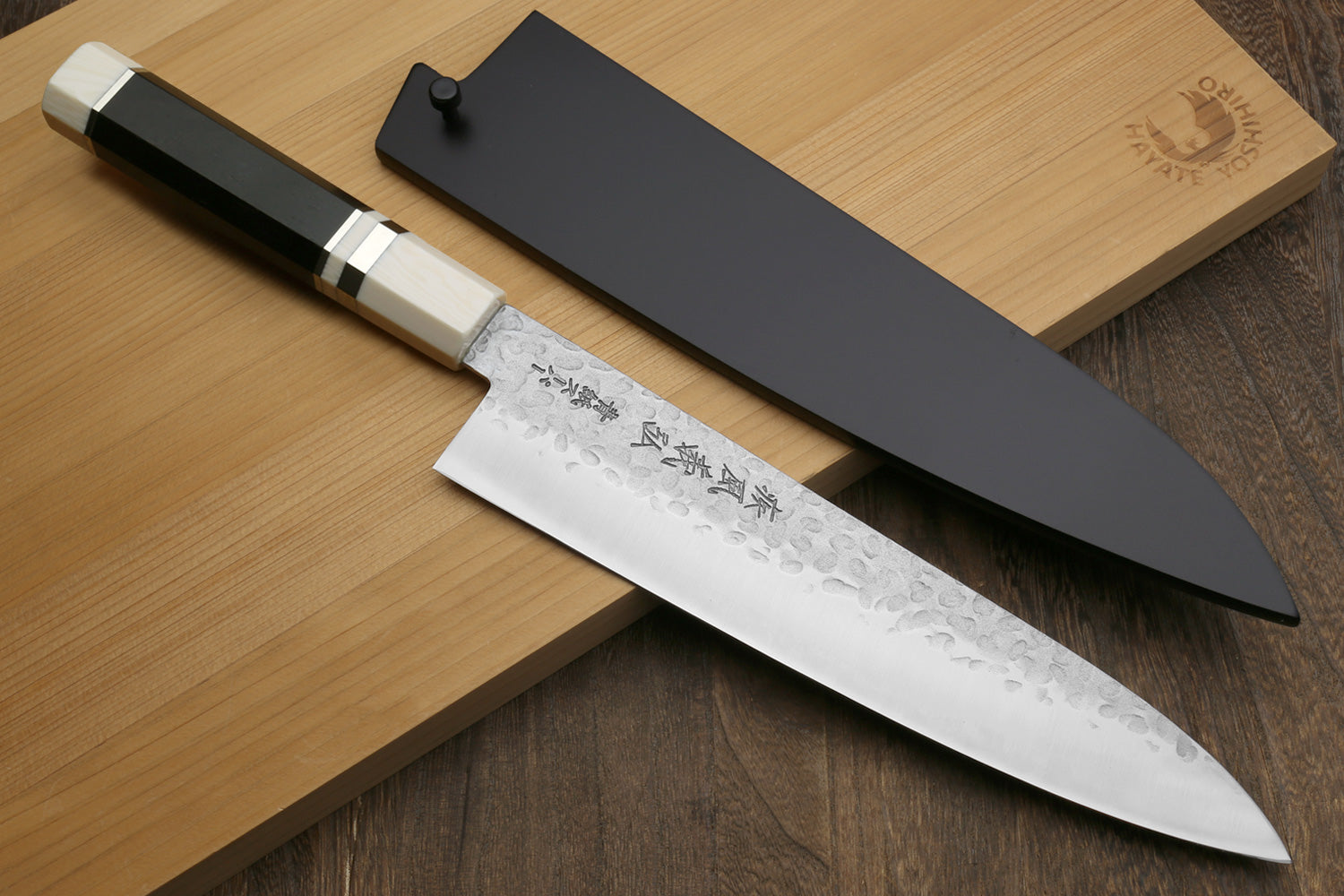 Hammered gyuto chef's knife with white blade, dark handle, off-white bolster
