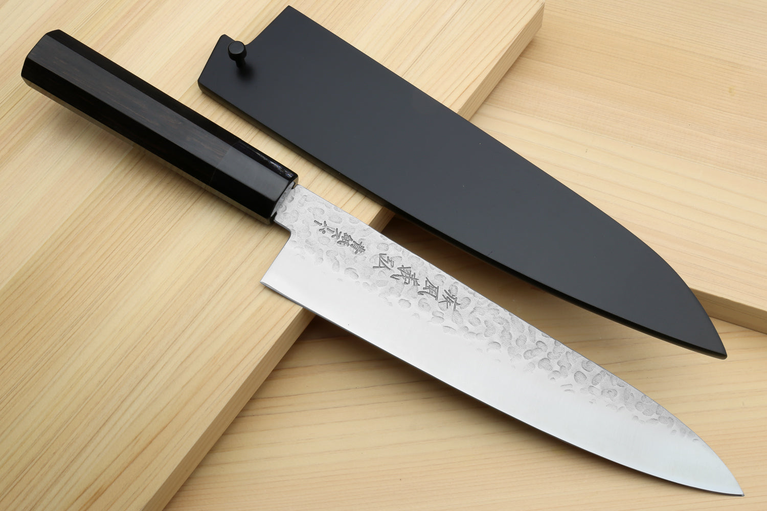 Hammered stainless gyuto chef's knife with ebony handle and dark sheath