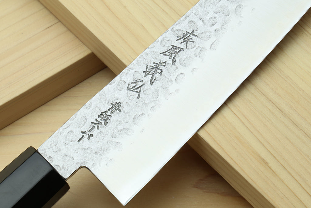Hammered stainless gyuto chef's knife blade close-up with etched characters