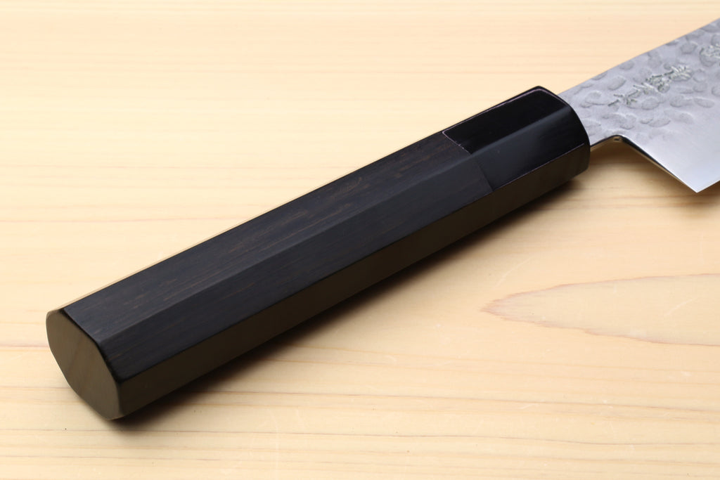 Ebony handle of a hammered stainless gyuto chef's knife with part of blade