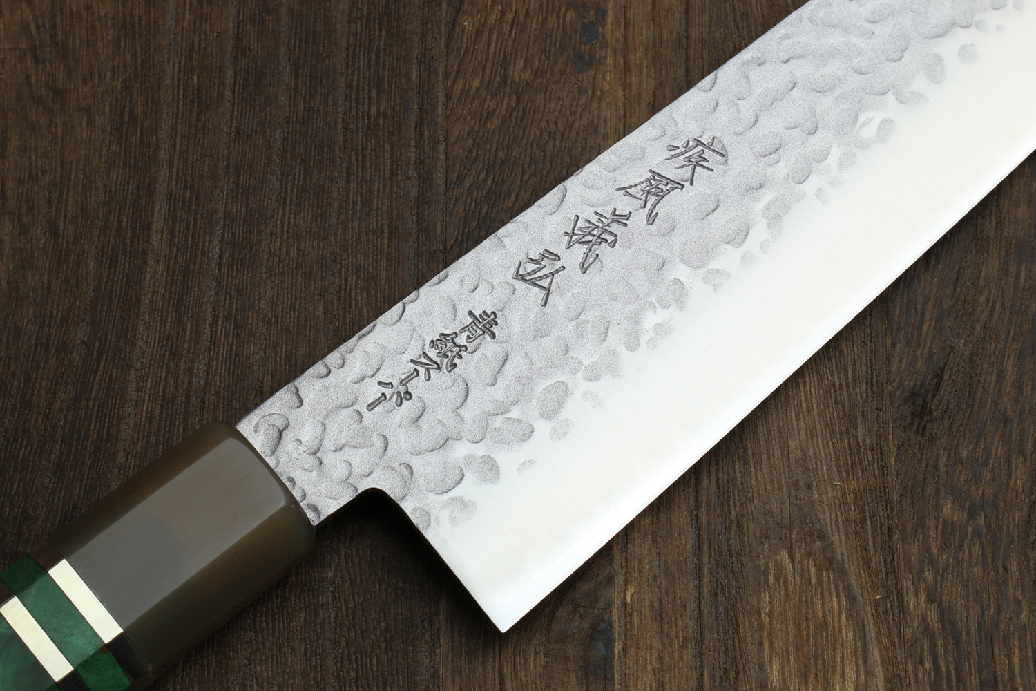 Gyuto chef knife blade close-up with hammered pattern and engraved markings