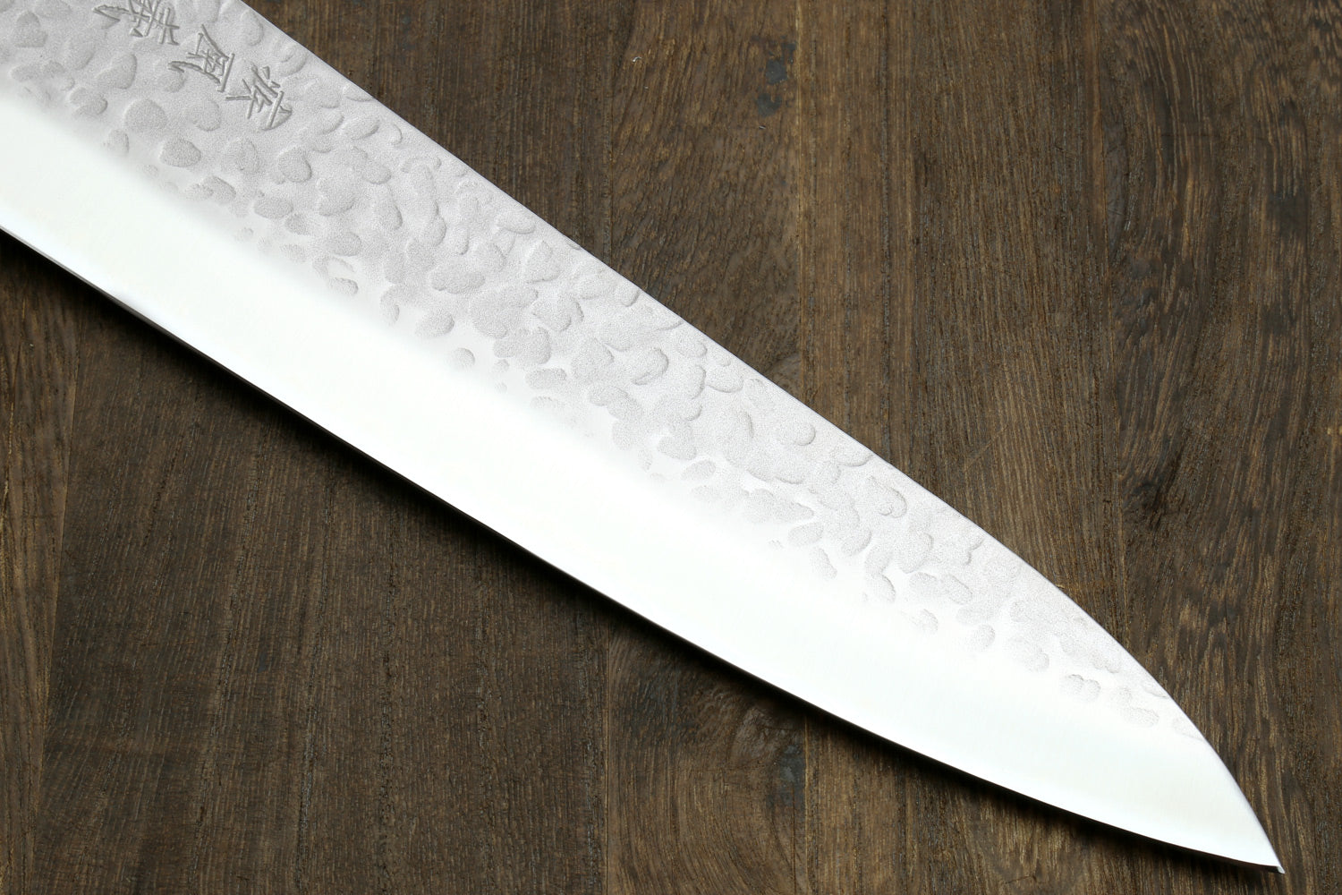 Gyuto chef knife blade edge close-up with hammered texture and pointed tip