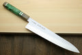 Gyuto chef knife with hammered stainless blade and green stabilised handle on board
