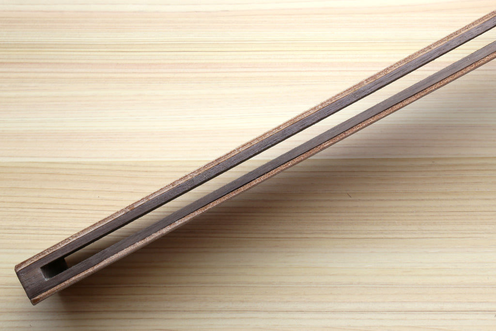 Long leather strop with wooden frame and dark edge trim on tan leather panel.
