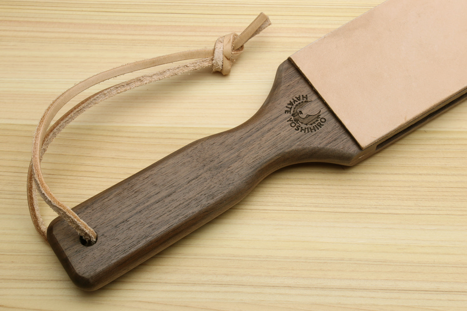 Wooden-handled leather strop with cord loop and light tan leather backing.