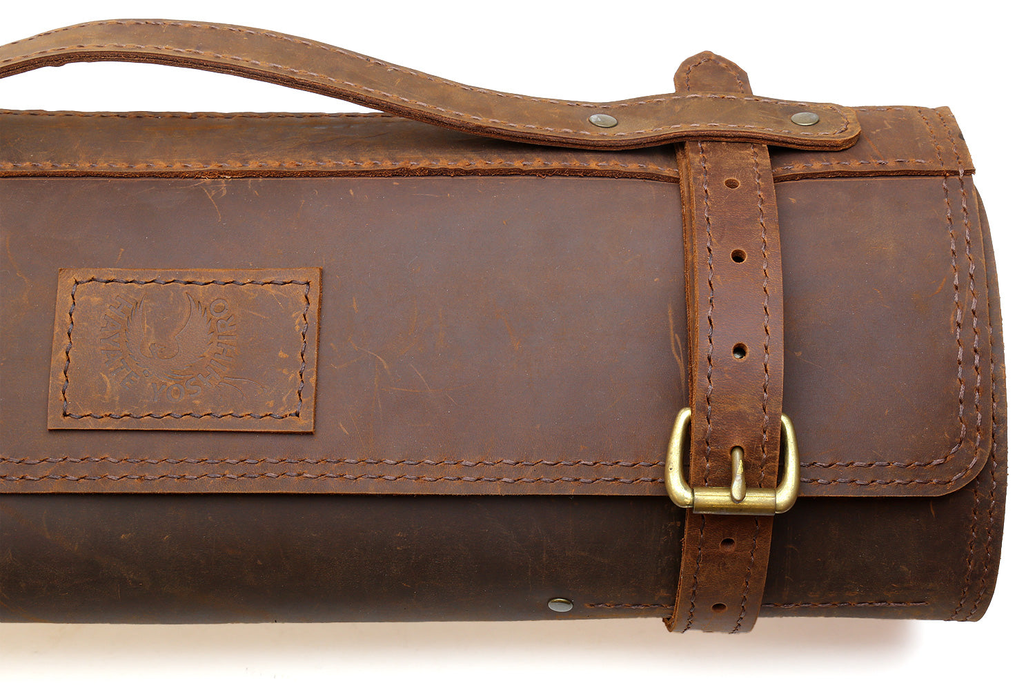 Brown leather knife roll bag close-up of stitched label and side buckle strap