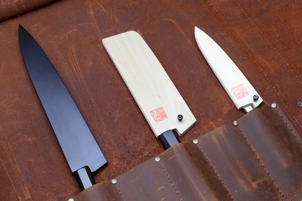 Brown leather knife roll with three knives in separate slots inside the divider