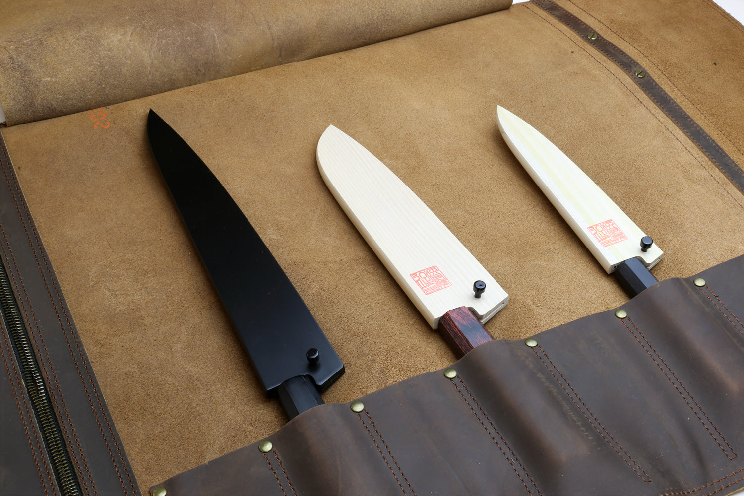 Brown leather knife roll case open, showing multiple knife slots and stitched panels.