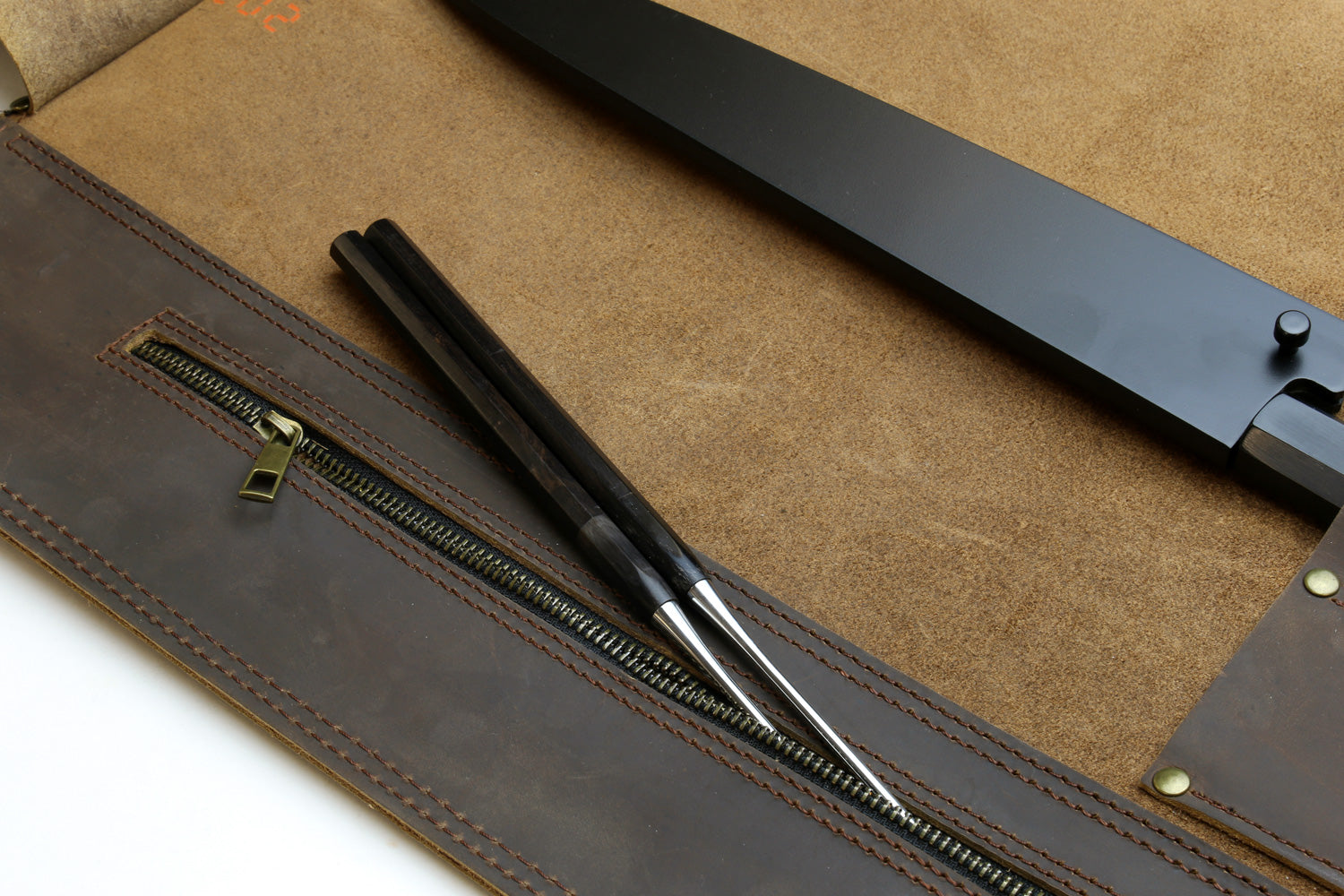 Brown leather knife roll case interior with zipper pocket and tool sleeves.