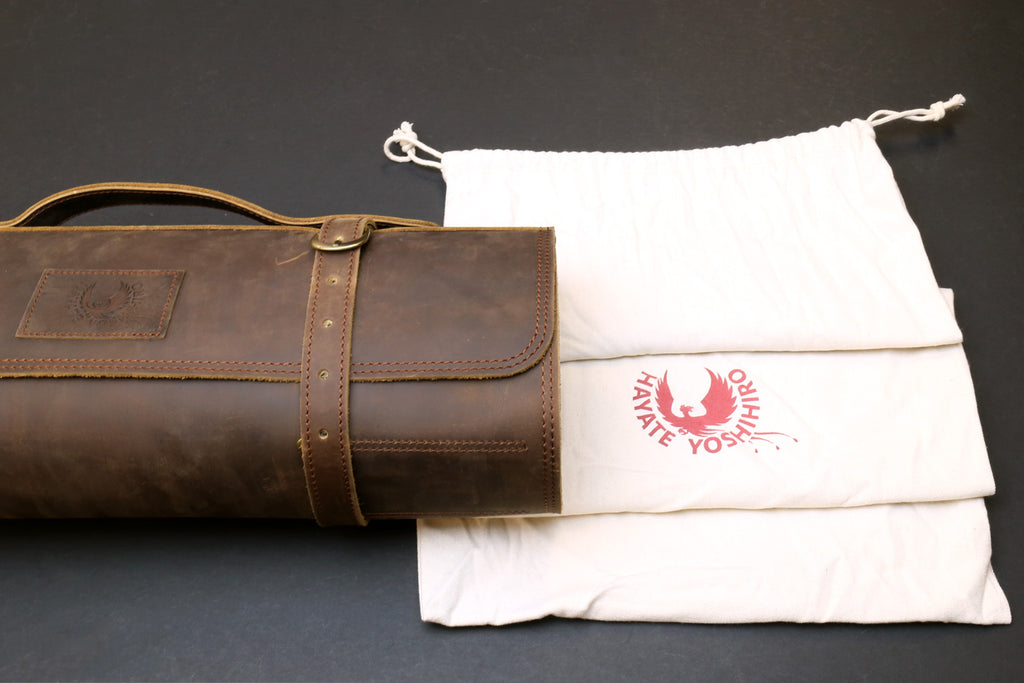 Brown genuine leather knife roll storage case with flap, wrap belt, and logo patch.