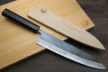 Chef's gyuto knife with black handle and blue steel blade on cutting boards