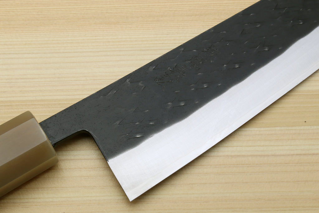 Kiritsuke chef knife blade close-up, dark kurouchi texture and bright silver edge