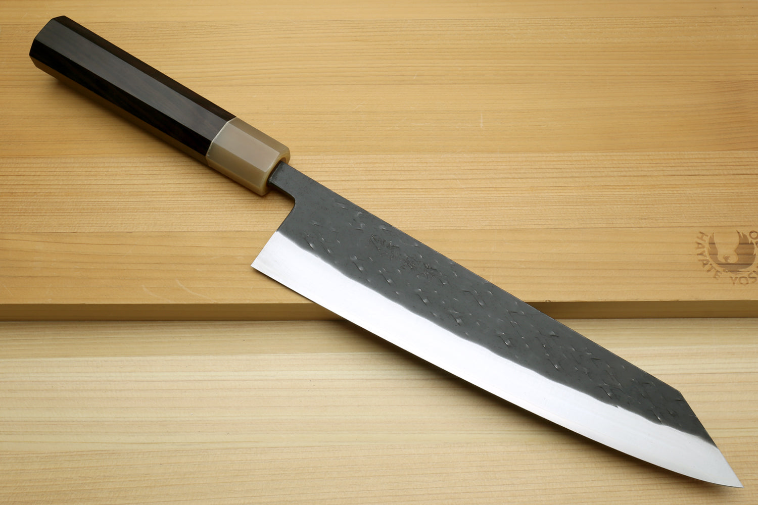 Kiritsuke chef knife with dark handle and textured black blade, silver cutting edge