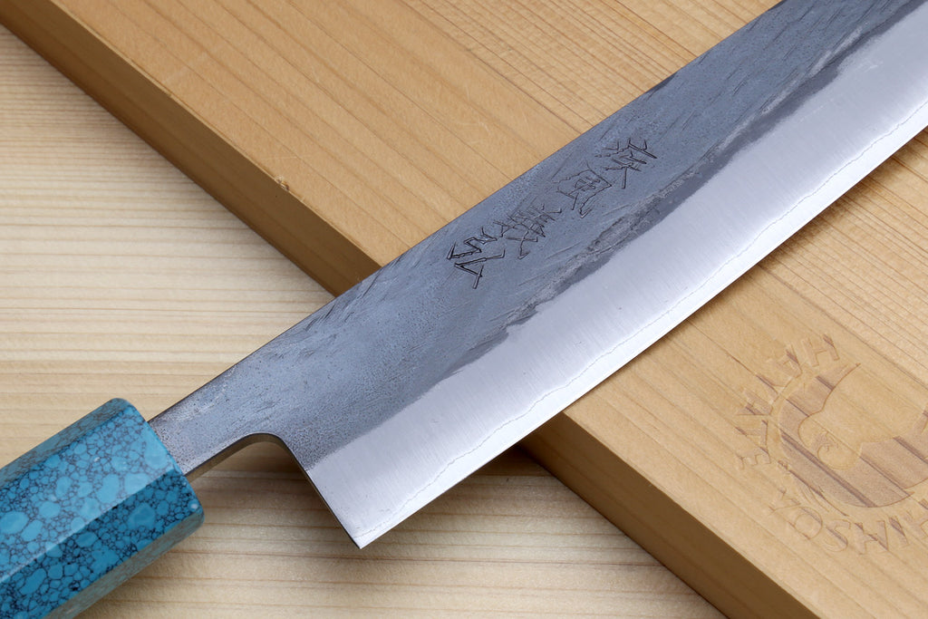 Sujihiki knife blade close-up with turquoise handle and polished cutting edge