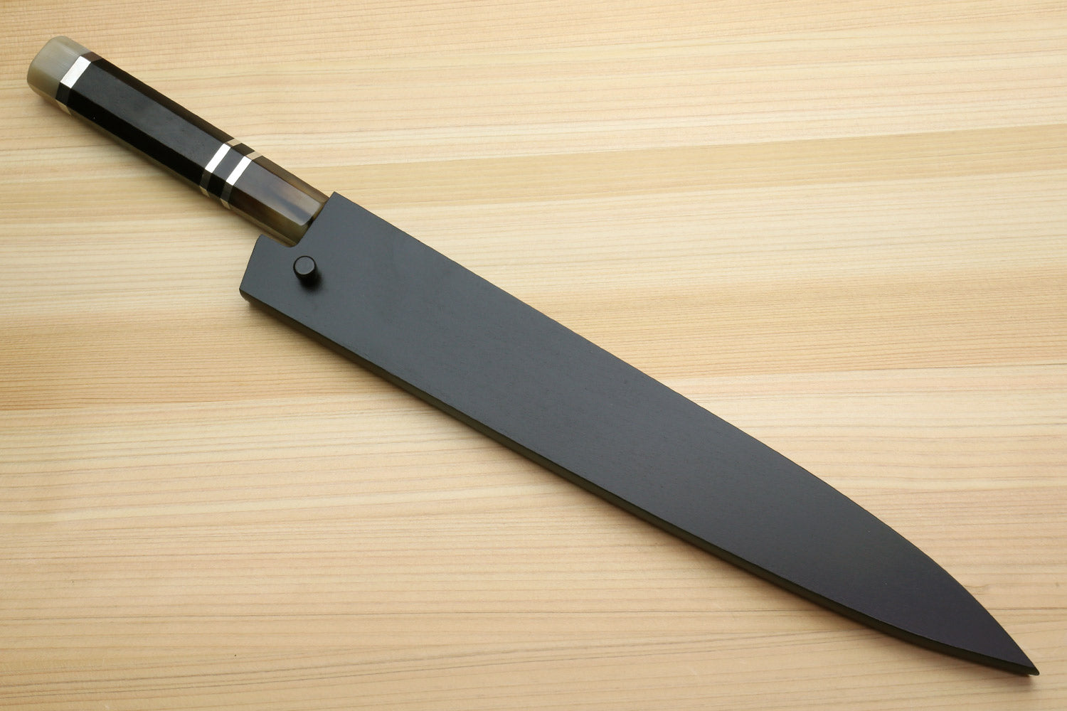 Kiritsuke slicer knife with black saya cover and dark handle on blade
