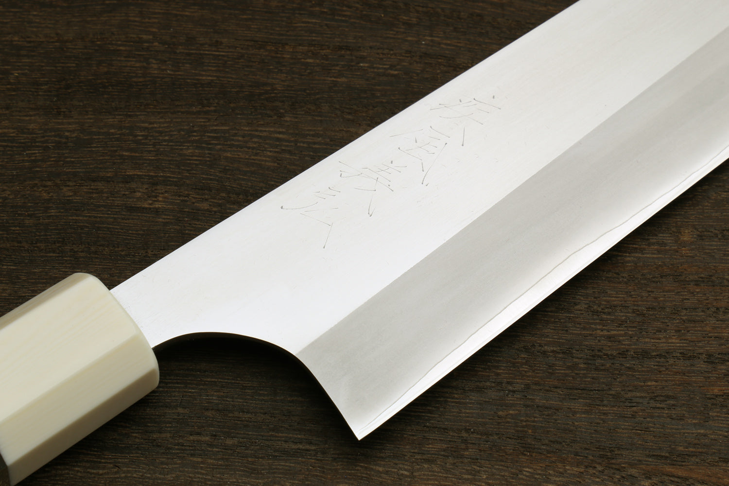 Close-up of gyuto knife blade edge with ivory bolster and ocean blue handle accent