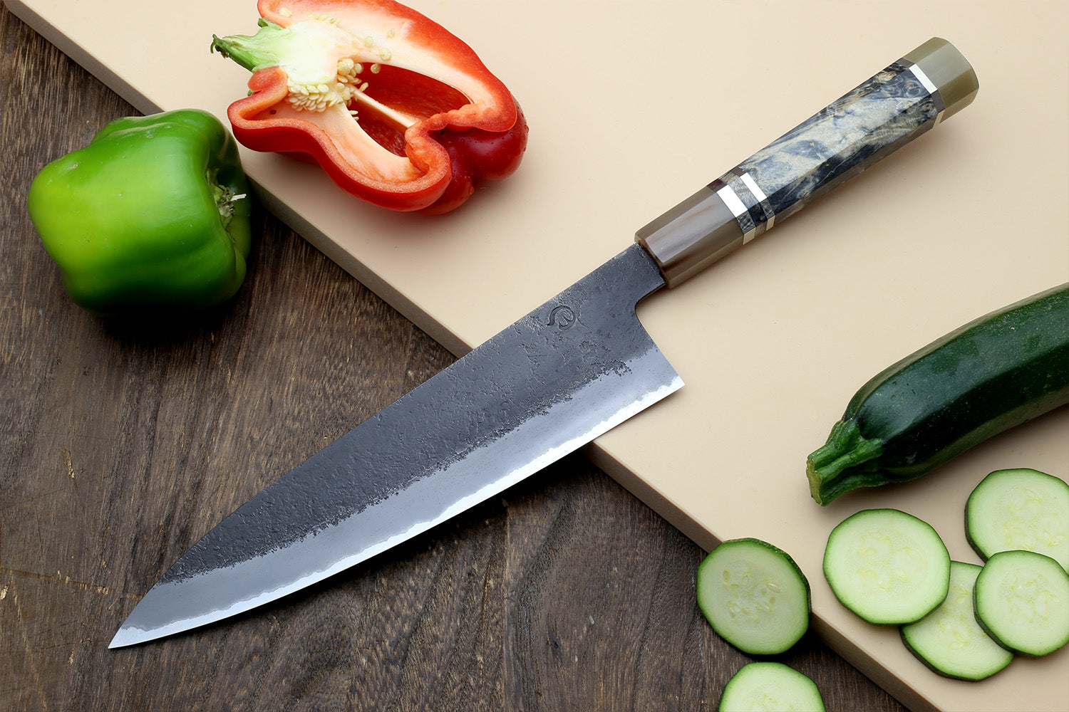 Gyuto chef’s knife, long dark blue mottled blade and beige handle with striped bolster.