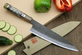 Gyuto chef’s knife with dark blue mottled blade, beige handle, and striped bolster detail.
