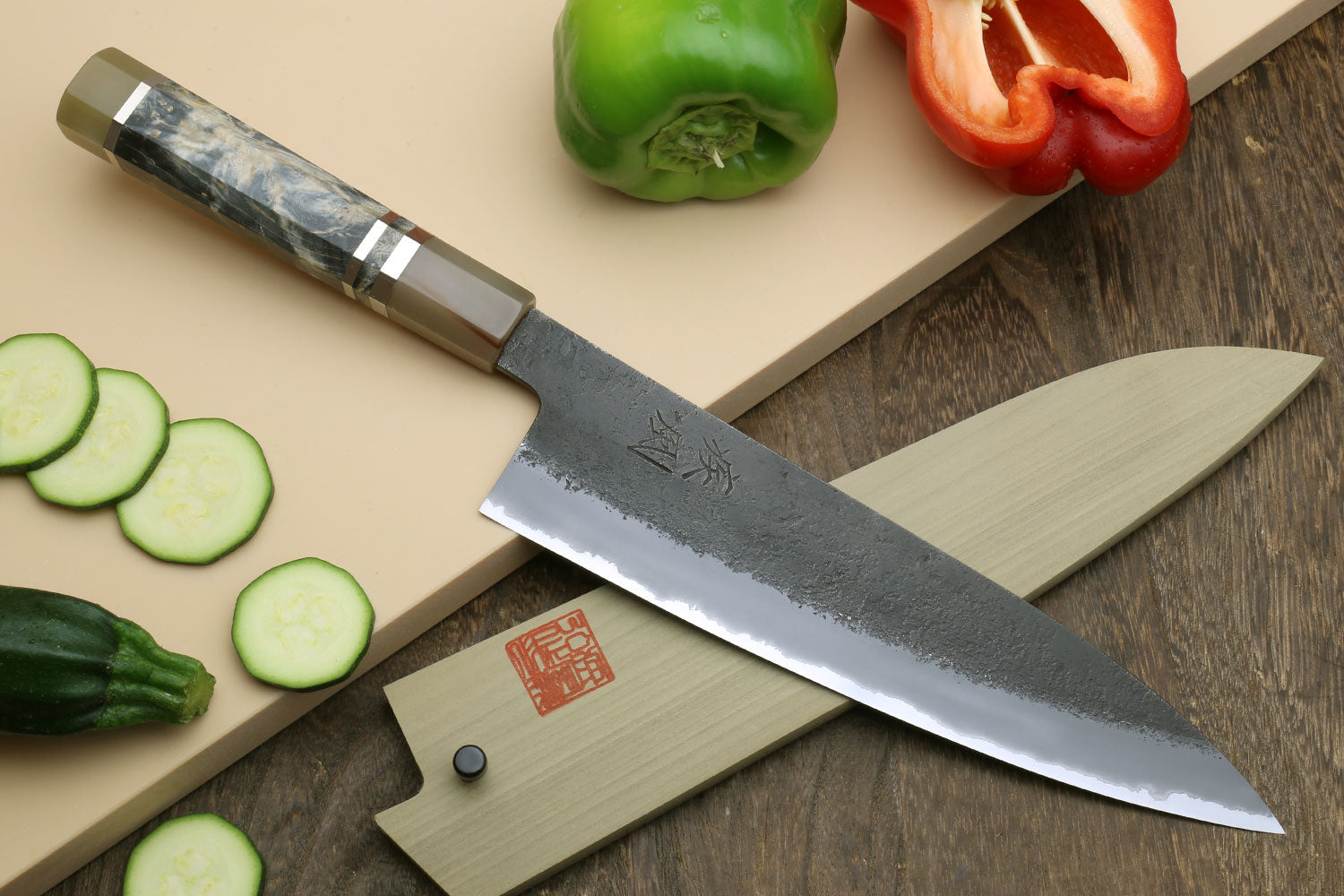Gyuto chef’s knife with dark blue mottled blade, beige handle, and striped bolster detail.