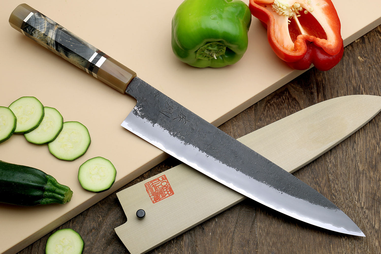 Black and silver stainless gyuto chef’s knife with textured blade and dark handle