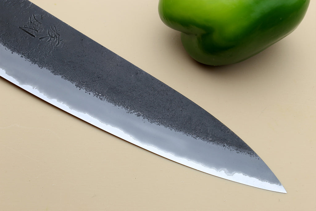 Gyuto chef’s knife, long pointed blade of dark blue mottled steel with stamped marks.